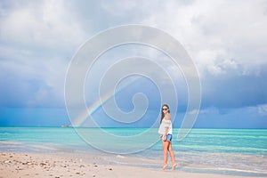 Beautiful happy woman on the beach with beautiful rainbow over the sea