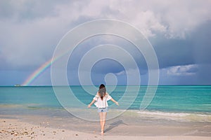 Beautiful happy woman on the beach with beautiful rainbow over the sea