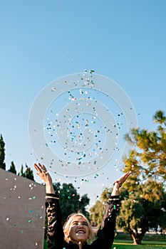 Beautiful happy woman at celebration party with confetti falling everywhere on her