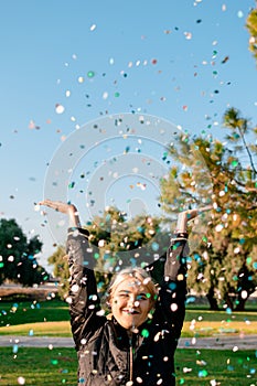 Beautiful happy woman at celebration party with confetti falling everywhere on her