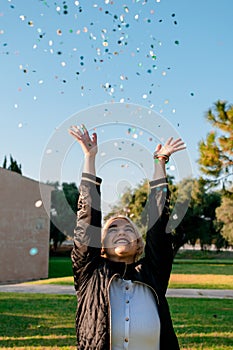 Beautiful happy woman at celebration party with confetti falling everywhere on her