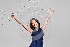 Beautiful happy woman at celebration party with confetti falling everywhere on her. Birthday or New Year eve celebrating concept photo