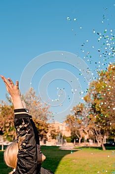 Beautiful happy woman at celebration party with confetti falling everywhere on her