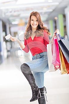 Beautiful happy woman with credit card and shopping bags in shopping mall