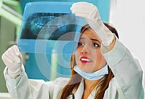 Beautiful happy woman doctor holding a X-Ray and watching teeth structure at dentist`s office