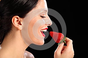 Beautiful happy woman eating red strawberry fruit