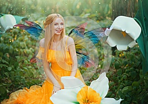 Beautiful happy woman fairy nymph sitting on forest. Magical fantasy wings costume pixie butterflies. Elf girl princess