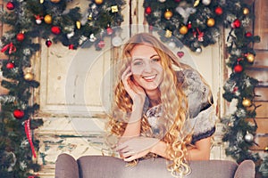 Beautiful happy woman in furcoat by the Christmas decorations