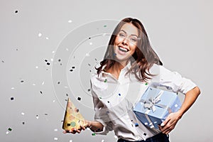 Beautiful happy woman with gift box at celebration party with confetti falling everywhere on her.