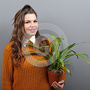 Beautiful happy woman holding plant in vase against gray background