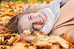 Beautiful happy woman lying on autumn leaves