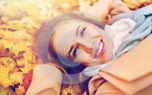 Beautiful happy woman lying on autumn leaves