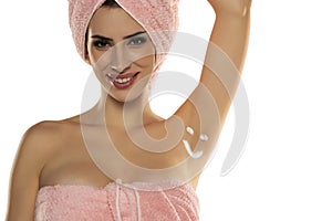 Beautiful happy woman posing with smile shaped cosmetics product on her underarm isolated on white