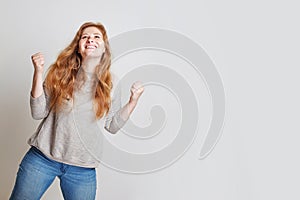 Beautiful happy woman with positive facial expression standing against white studio wall background, portrait