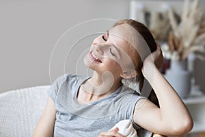 Beautiful happy woman relaxing closed her eyes on cozy chair in living room