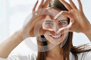 Beautiful Happy Woman Showing Love Sign Near Eyes. photo