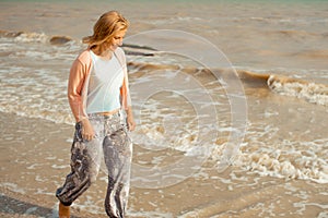 Beautiful happy woman smiling and walking on the sea shore