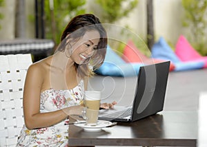 Beautiful happy woman in Summer dress outdoors at nice coffee shop having breakfast networking or working with laptop computer