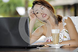 Beautiful happy woman in Summer dress outdoors at nice coffee shop having breakfast networking or working with laptop computer