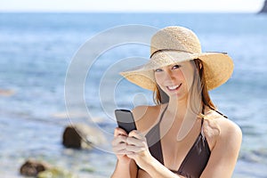 Beautiful happy woman texting on a smart phone on the beach