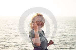 Beautiful happy woman tourist looking at camera with beautiful sea view with wind in hairs with sea beach background