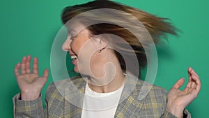 Beautiful happy woman turning her head and waving her blondehair. Isolated on a green background.