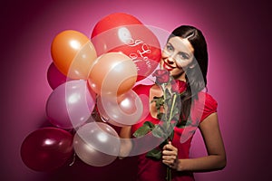 Beautiful happy woman with valentines day balloon on pink background