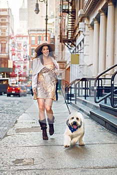 Beautiful happy woman walking with a dog at the street of New York City