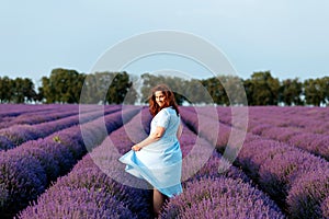 Beautiful and happy woman walks in a lavender field at sunset