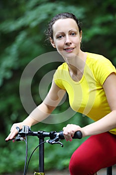 Beautiful happy woman in yellow rides bicycle in