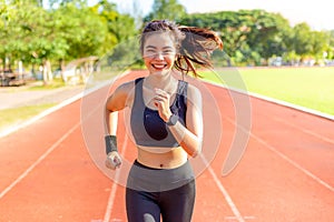 Beautiful happy young Asian woman running for her morning exercise at a running track, healthy lifestyle