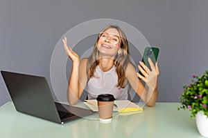 Beautiful happy young business woman uses her phone while working in startup office