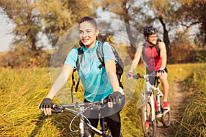 Happy young woman riding mountain bike with her boyfriend