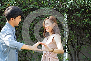 Beautiful happy young couple fun making gesture heart shape with hand outdoor together,