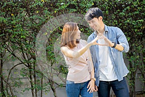 Beautiful happy young couple fun making gesture heart shape with hand outdoor together,