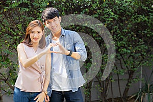 Beautiful happy young couple fun making gesture heart shape with hand outdoor together