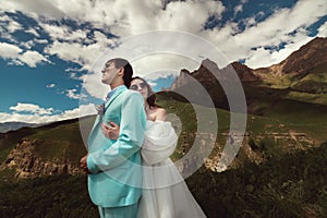 Beautiful happy young couple in love hugging in the mountains, against the backdrop of a beautiful landscape. Wedding