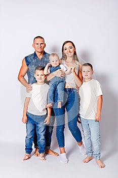 Beautiful happy young family with three children in denim dress on white background