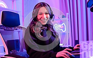 Beautiful happy young female game online streamer or caster smiling with fun, succeed for winner, using computer to play, sitting