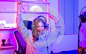 Beautiful happy young female game online streamer or caster smiling with fun, succeed for winner, using computer to play, sitting
