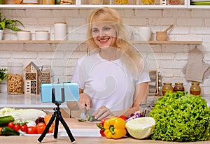 A beautiful happy young girl is blogging for her kitchen channel about a healthy lifestyle and new recipes in the kitchen of her