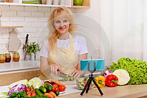 A beautiful happy young girl is blogging for her kitchen channel about a healthy lifestyle and new recipes in the kitchen of her