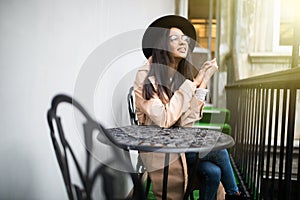 Beautiful happy young girl in a hat resting outdoors in cafe