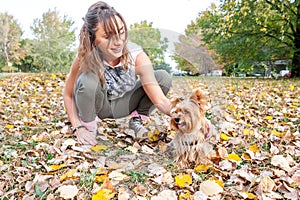 Beautiful happy young girl with her Yorkshire terrier dog puppy enjoying and playing in the autumn day in the park selective focus