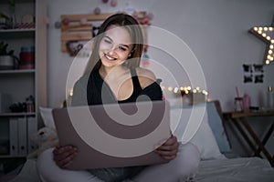 Beautiful happy young girl with laptop sitting and smiling, online dating concept.