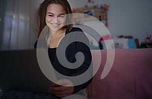 Beautiful happy young girl with laptop sitting and smiling, online dating concept.