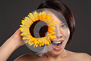 Beautiful happy young girl sunflower to her face