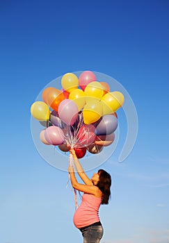 Beautiful happy young pregnant woman girl outdoors with balloons