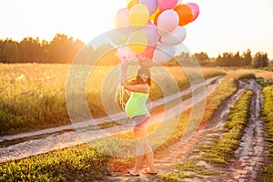 Beautiful happy young pregnant woman girl outdoors with balloons