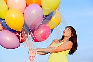 Beautiful happy young pregnant woman girl outdoors with balloons